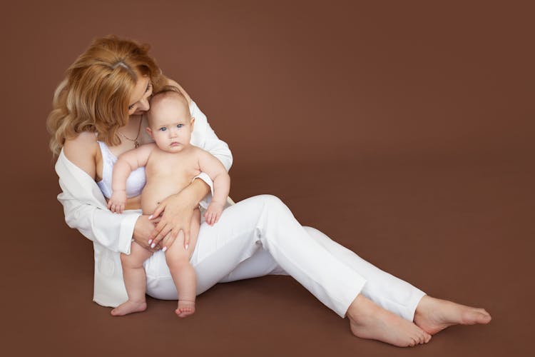 Young Mother And Baby On Brown Studio Background