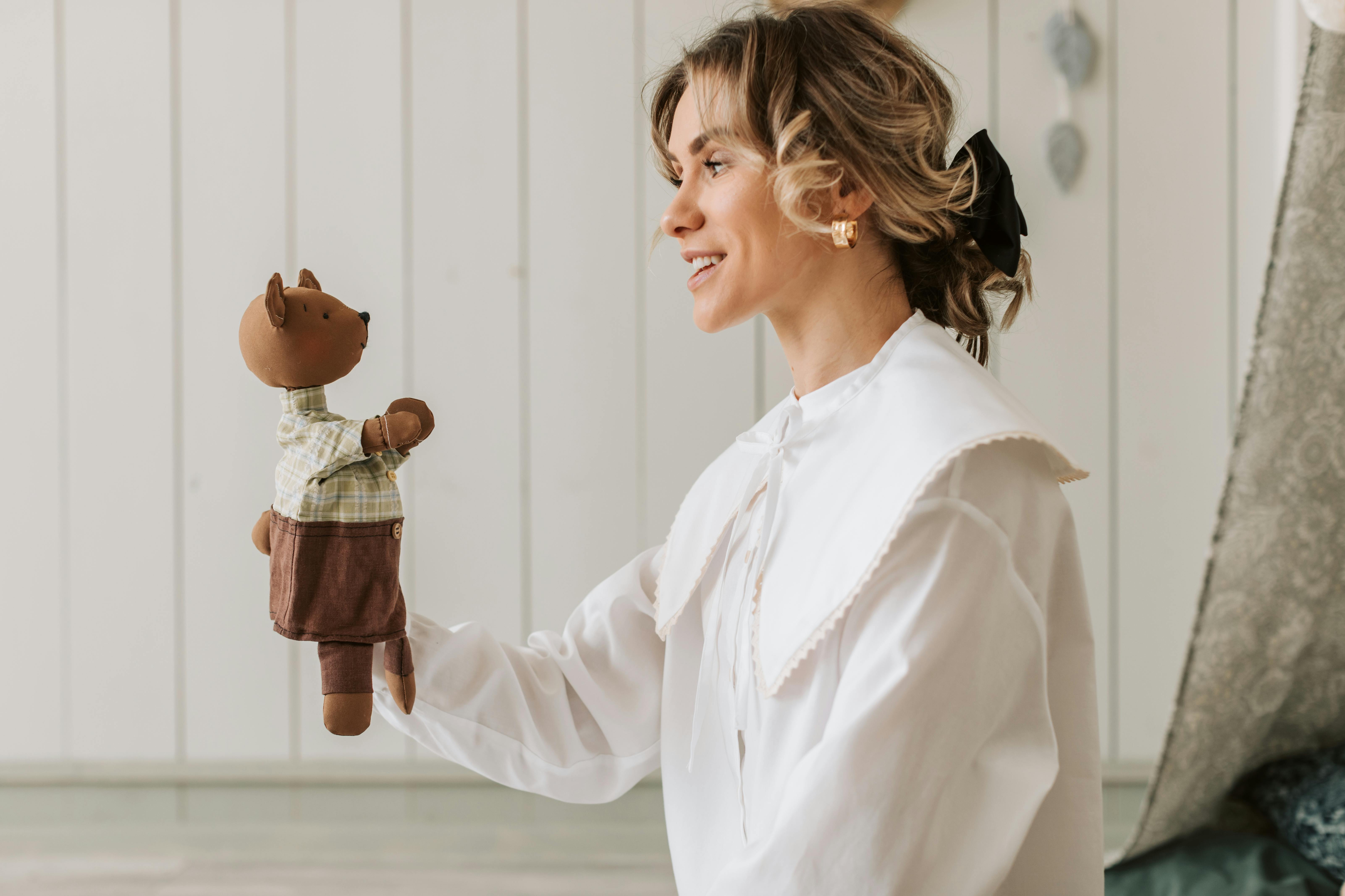 Free Smiling woman holding a bear puppet indoors, showcasing interaction and joy. Stock Photo