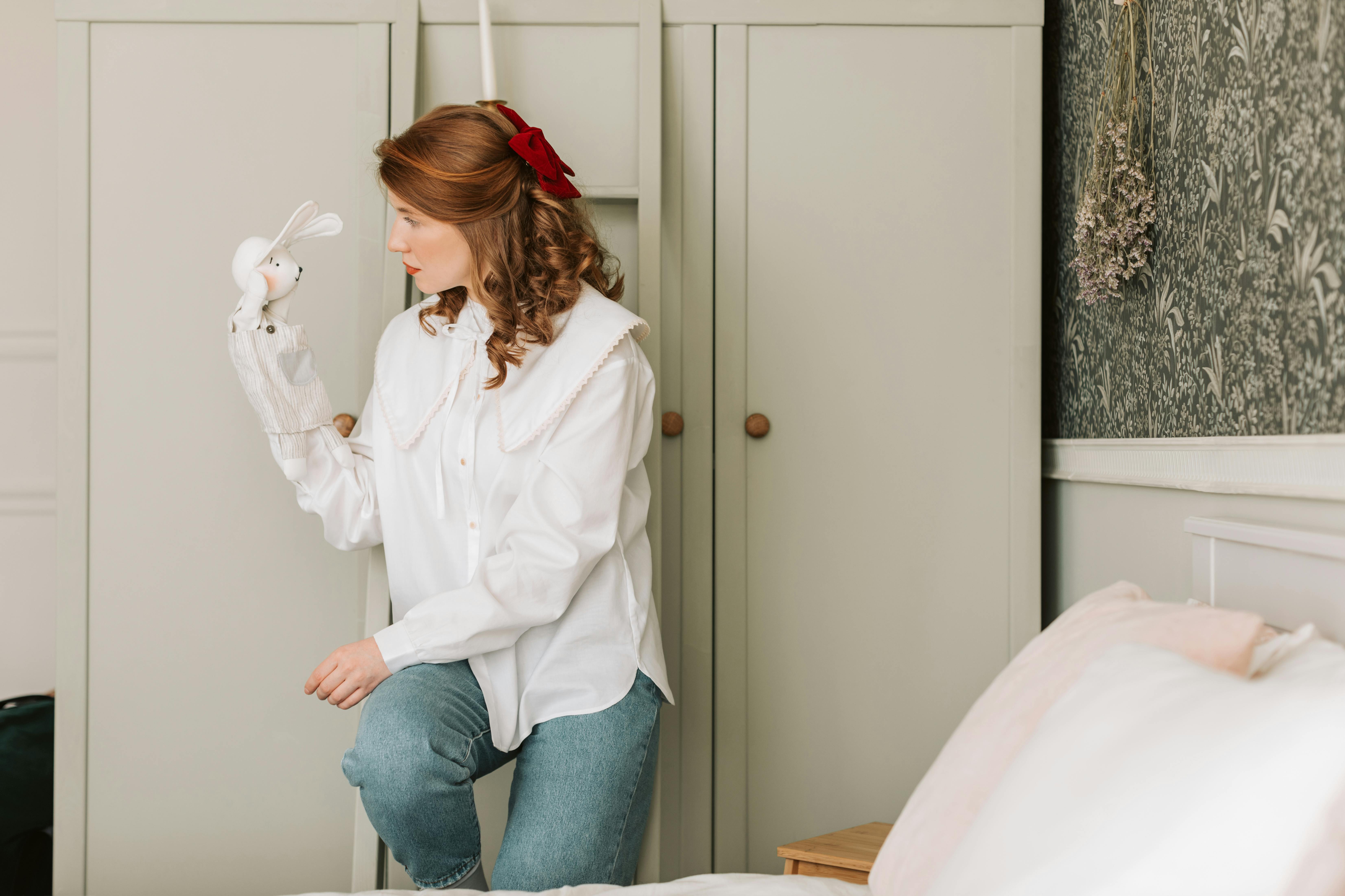 A woman interacts with a rabbit puppet indoors, showcasing a leisure activity.