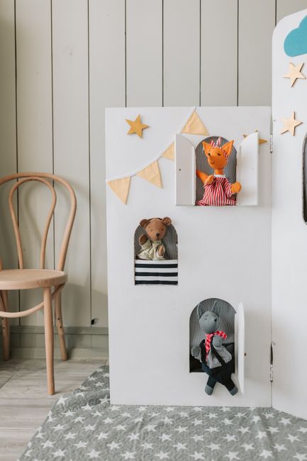 An indoor puppet theater scene with playful animal puppets and star decorations.