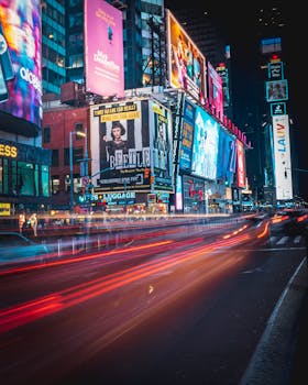 Vibrant night scene in Times Square, NYC, with colorful billboards and motion-blurred traffic.