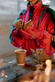 Woman enjoying a warm drink and pastry in winter attire, perfect for cozy cold weather moments.