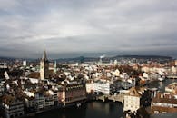 在多云的天空下，俯瞰苏黎世历史悠久的城市景观，欣赏钟楼和运河的壮丽景色