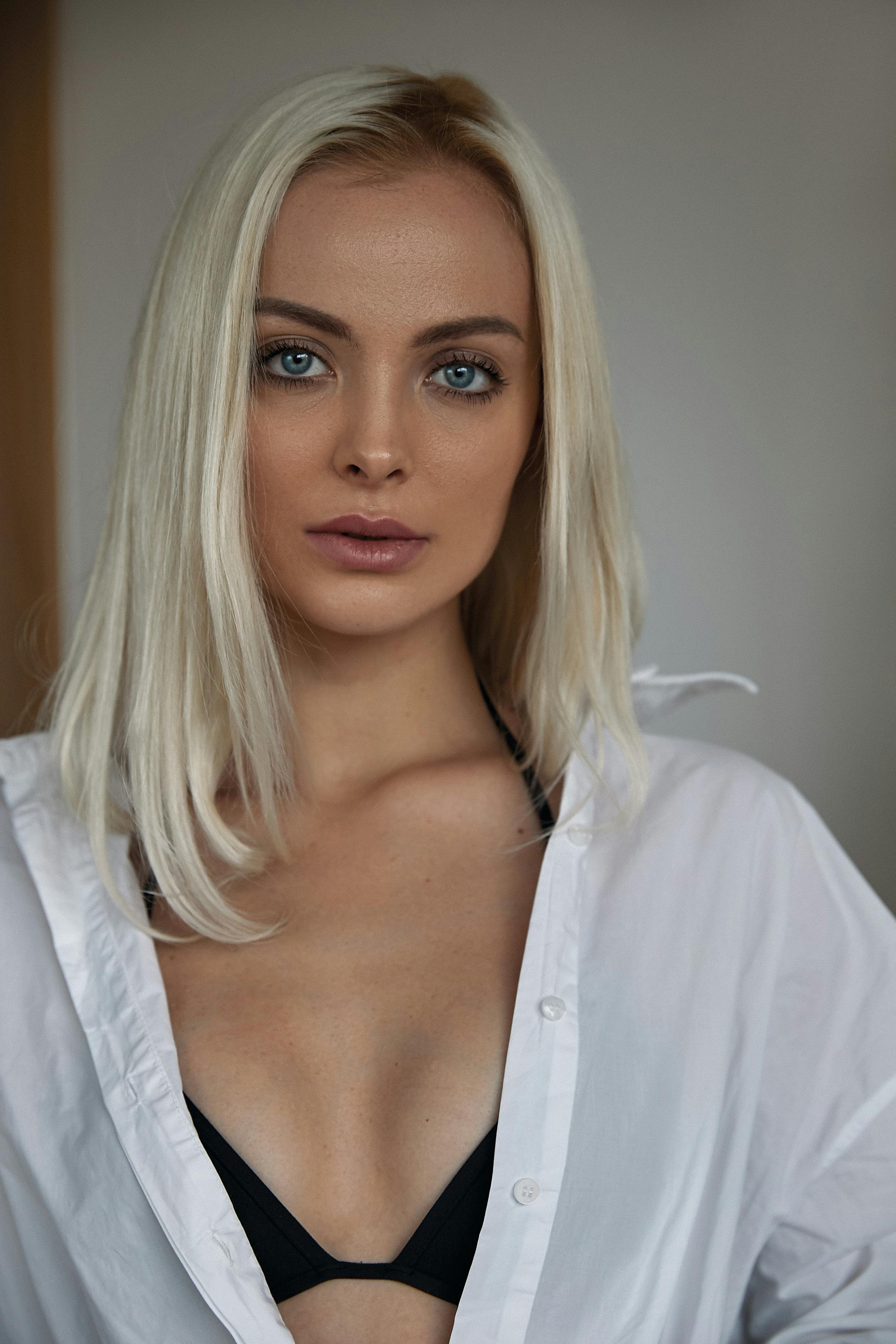 A captivating portrait of a blonde woman in a white shirt, exuding elegance.