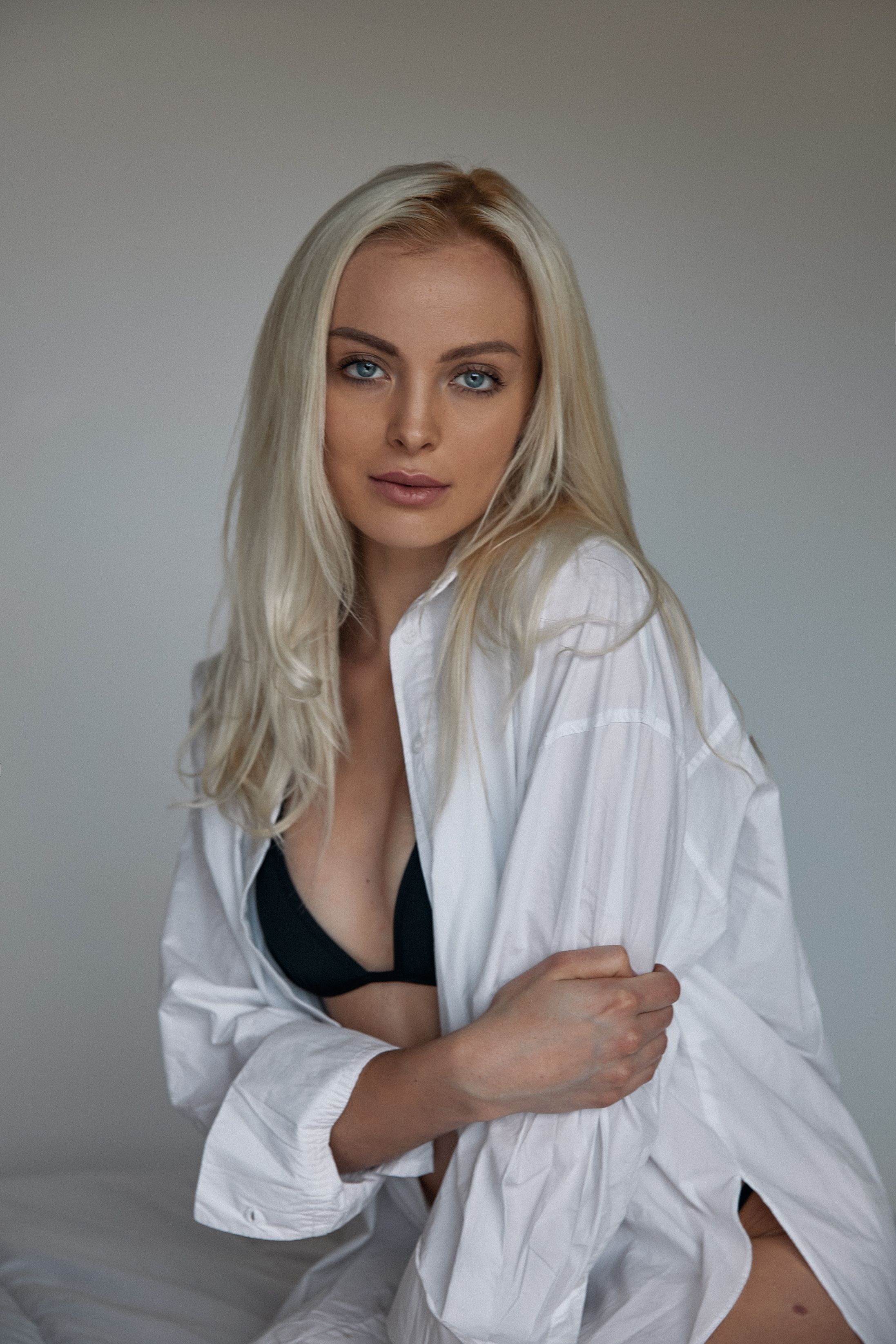 Portrait of a blonde woman wearing a white shirt and black lingerie, exuding elegance.