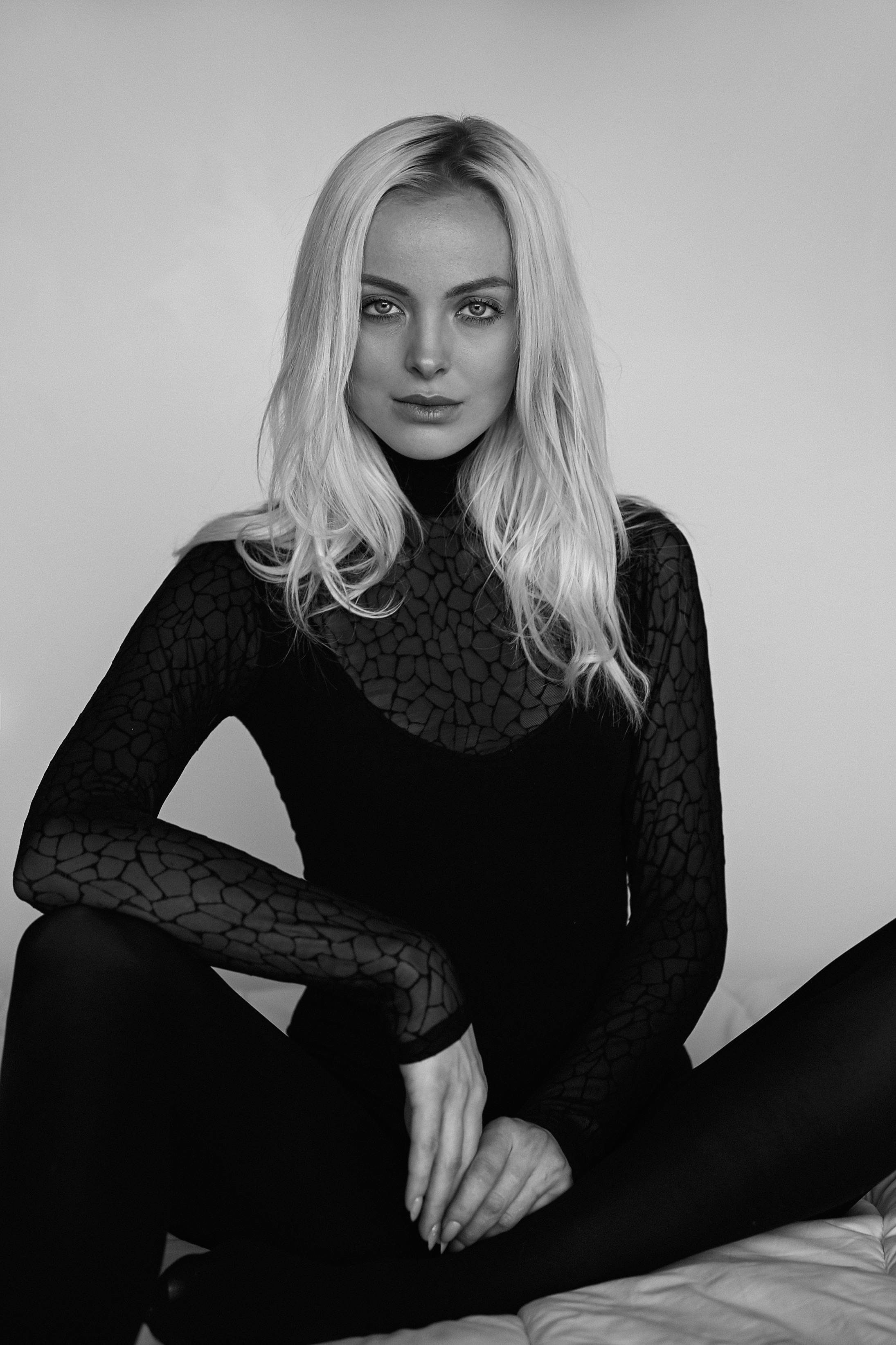 Black and white portrait of a fashion model posing elegantly in a studio setting.