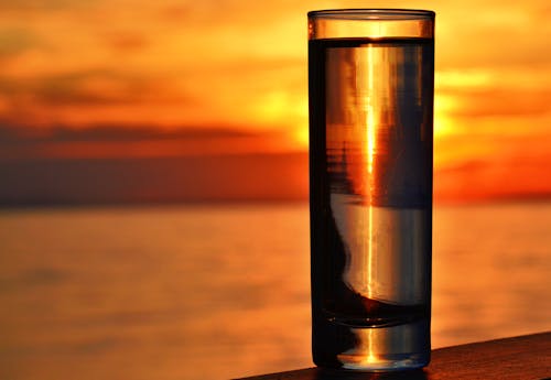 Free Clear Highball Glass on Brown Surface during Golden Hour Stock Photo