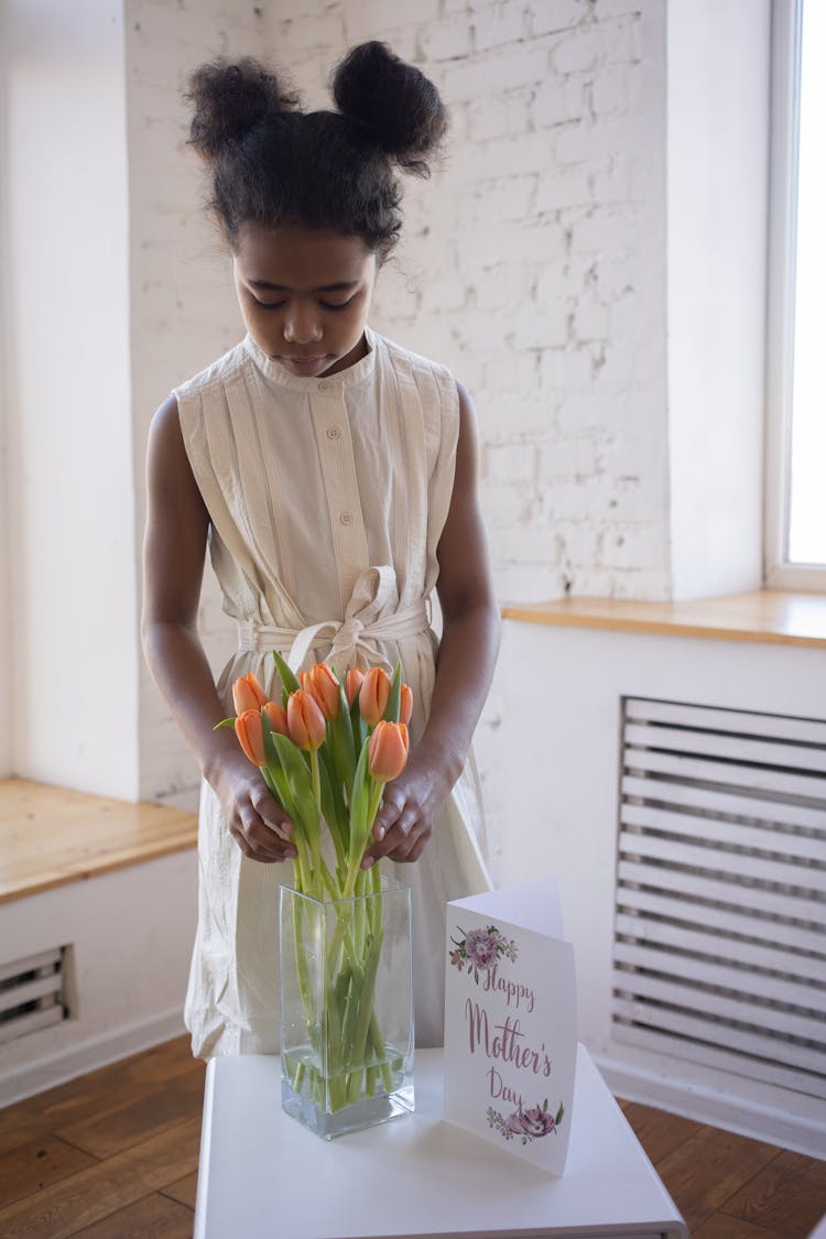 A Girl Arranging The Flowers In The Vase