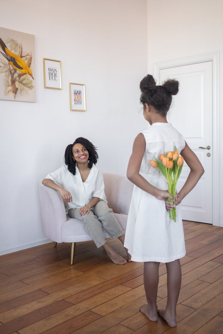 Woman Sitting On Chair Facing A Child Standing With Hands Behind Back