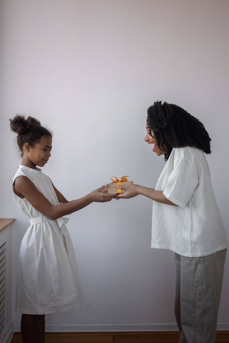 A Woman And Child Holding A Gift Box Facing Each Other