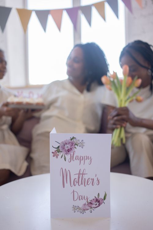 Free A joyful Mother's Day celebration with a greeting card, flowers, and family indoors. Stock Photo