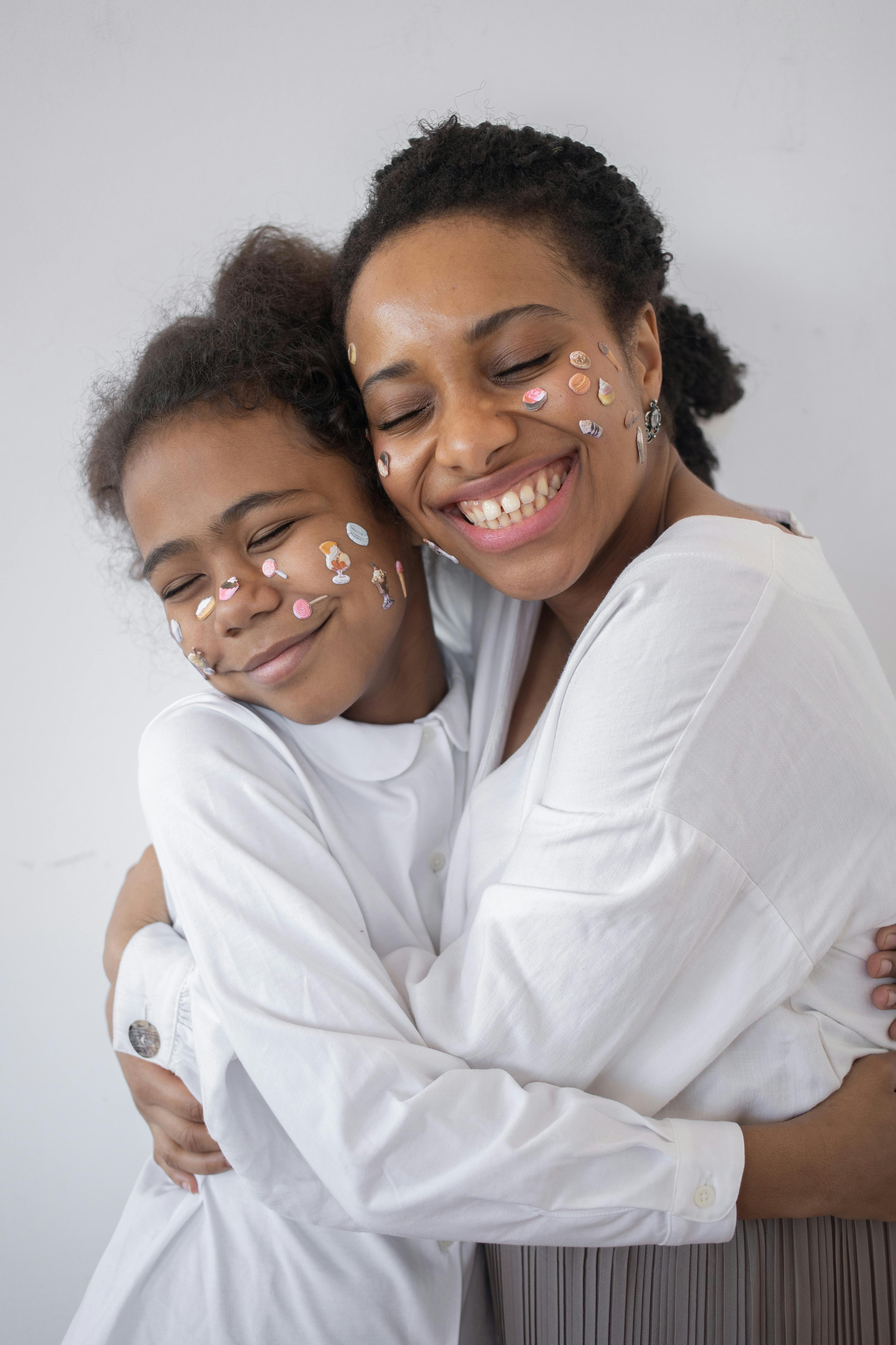 A joyful mother and daughter embracing with face stickers, symbolizing love and happiness.