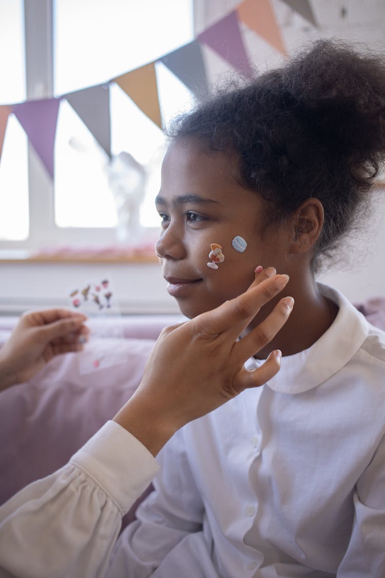 A Person Putting Stickers On The Girl's Face