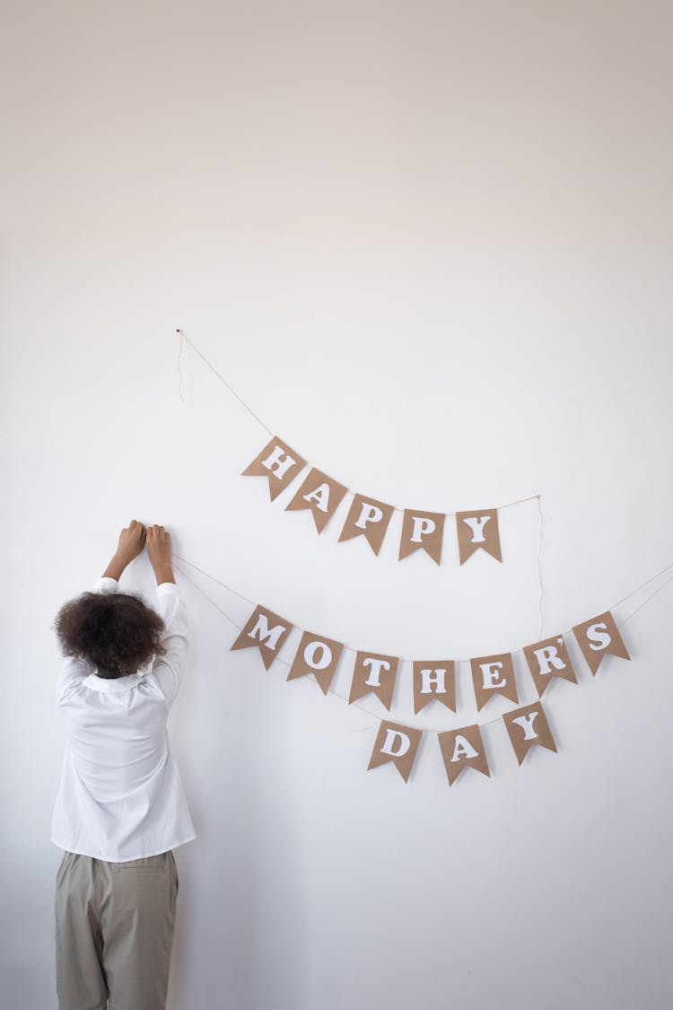 Child Setting Up A Mother's Day Banner