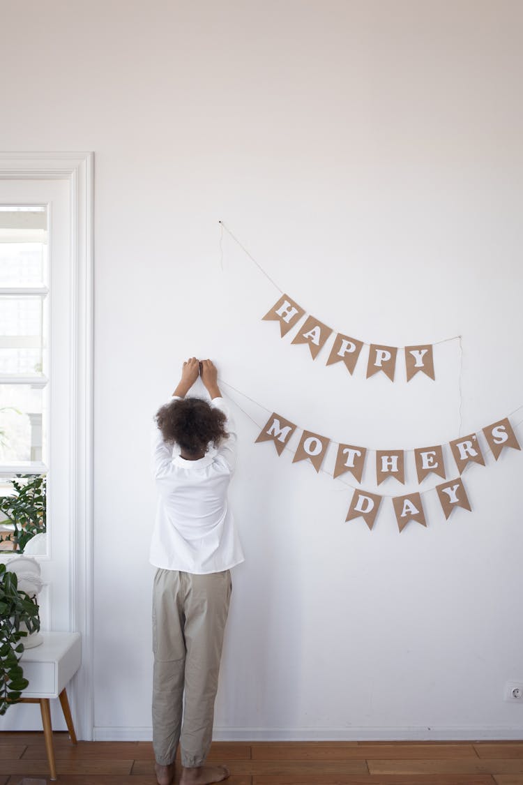 Kid Hanging A Banner On A Wall