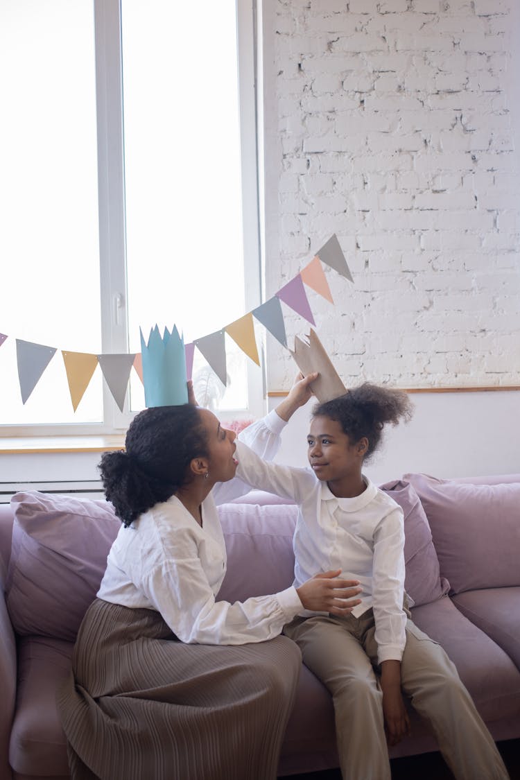 Mother And Child Putting Paper Crowns On Their Head