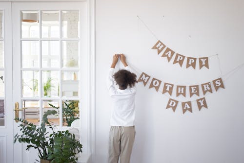 A Girl Hanging a Banner on a White Wall