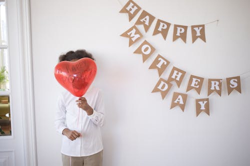 Free A Child Standing with a Balloon in Front of Their Face on Their Birthday  Stock Photo