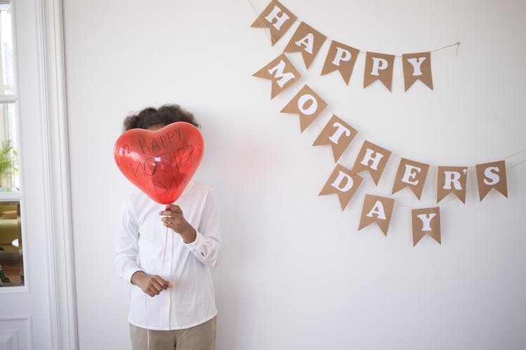 A Child Standing With A Balloon In Front Of Their Face On Their Birthday 