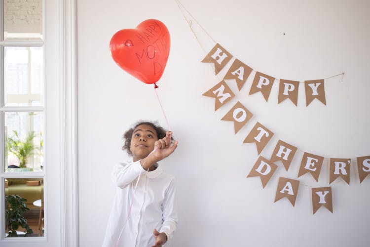 Girl In White Long Sleeve Shirt Holding Red Heart Balloon