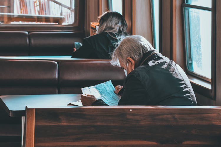 Old Man Reading Newspaper In Cafe