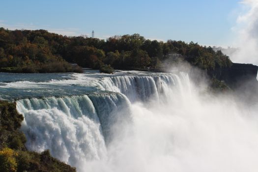 Experience the breathtaking beauty of Niagara Falls with vibrant autumn foliage.