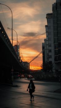 A silhouetted woman walks in urban İstanbul during a vibrant sunset, capturing the city's lively atmosphere.
