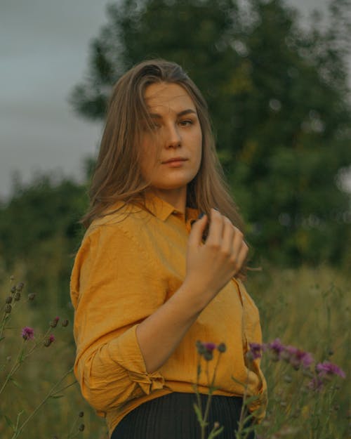 Free Woman in Yellow Dress Shirt Standing in a Flower Field Stock Photo