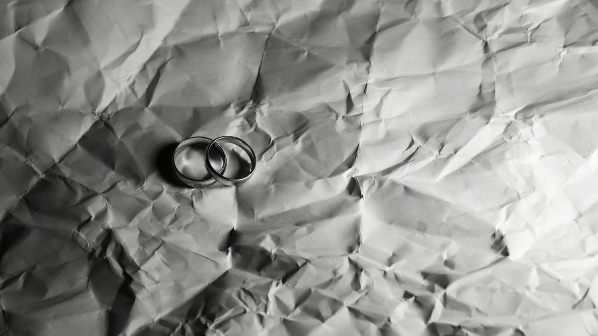 クシャクシャになった紙の上に置かれた2つの結婚指輪