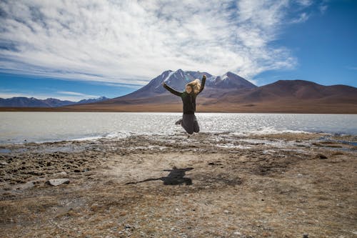 A Woman Jumping Near a Lake