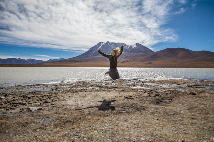 A Woman Jumping Near A Lake