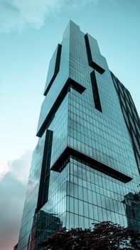 Stunning modern skyscraper with glass panels under a clear blue sky, viewed from below.
