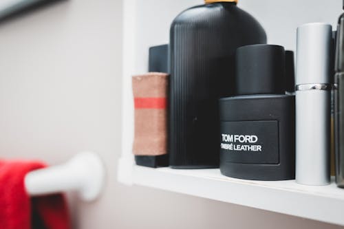 Stylish bottles with male perfume and cologne placed on shelf in light bathroom