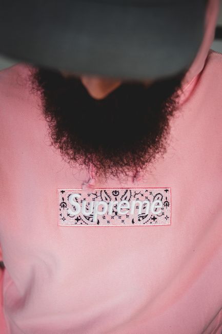 Close-up of a stylish pink hoodie featuring bold logo design and sharp fashion aesthetic.