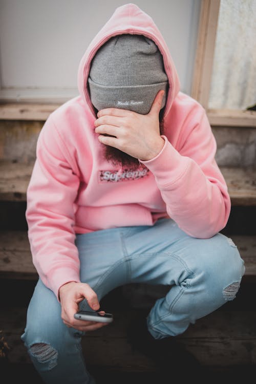 Free Male on stairs covering face and browsing phone Stock Photo