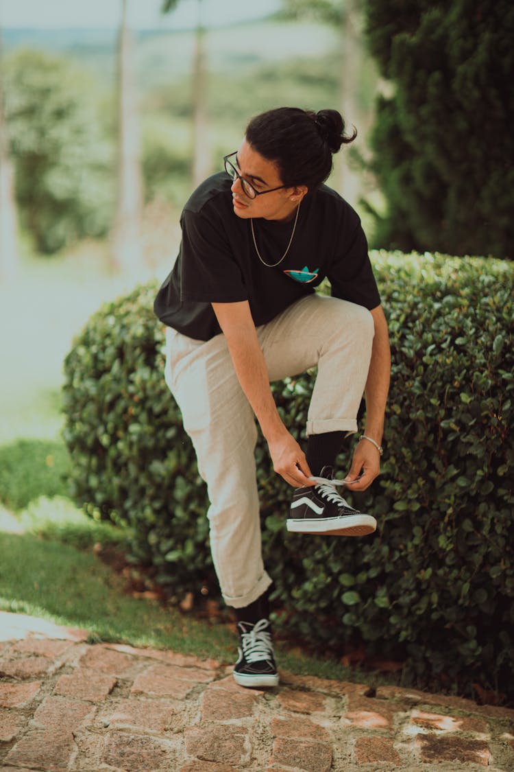 A Man In Black Shirt Tying His Shoelace