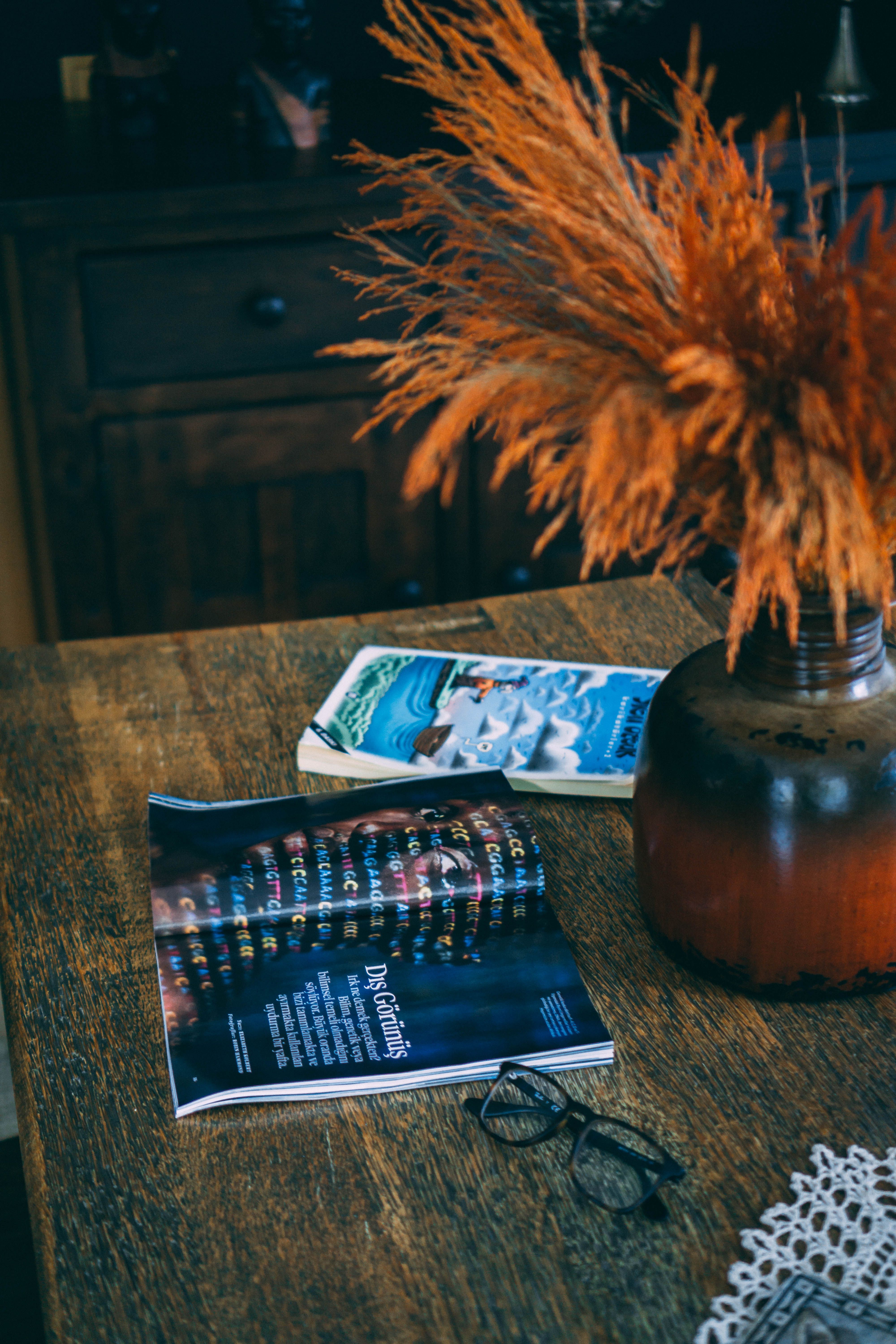 Rustic wooden table with magazines, black eyeglasses, and a vintage vase adding a cozy feel.