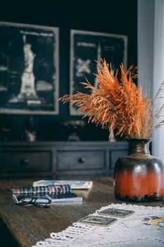 Warm and inviting autumn setting with a rustic vase filled with wheat, cozy decorations, and books.