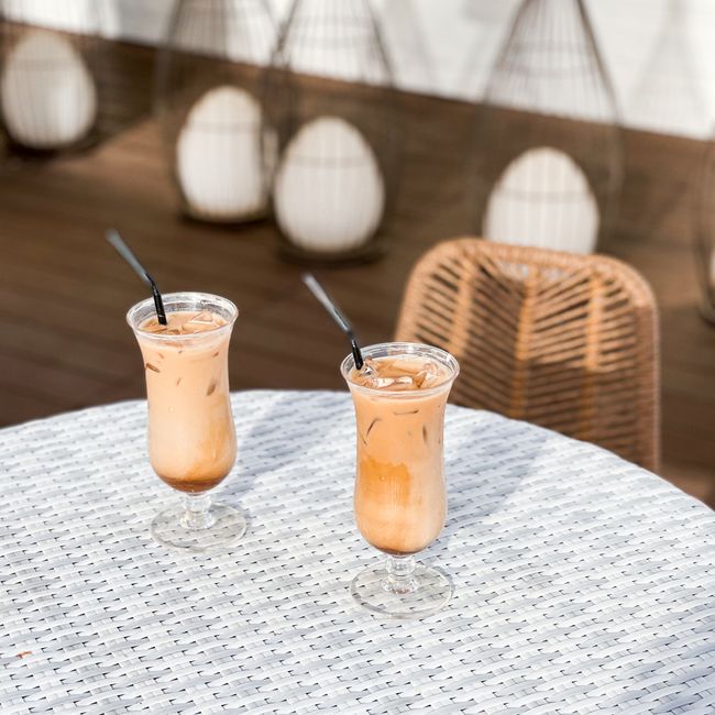 Two iced coffee drinks on a wicker table outdoors, ideal for a summer's day.