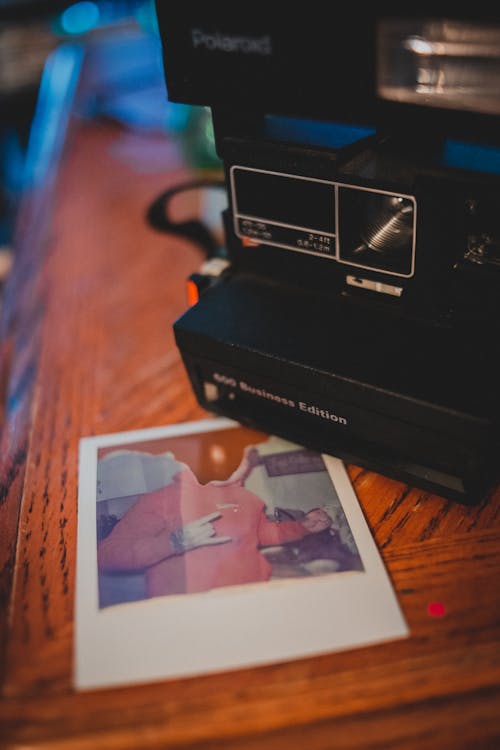 From above of retro photo camera with damaged picture placed on wooden table