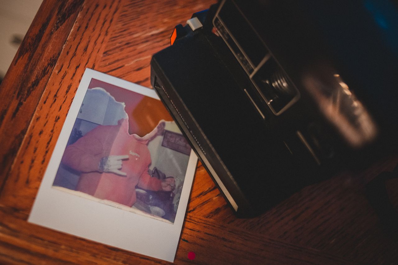 Top view of instant old fashioned camera placed on wooden table near torn picture