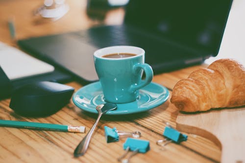 Close-Up Shot of a Cup of Coffee beside a Croissant