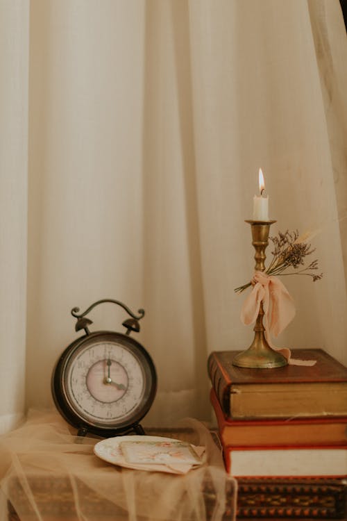 Free Alarm Clock Beside a Lighted Candle Stock Photo