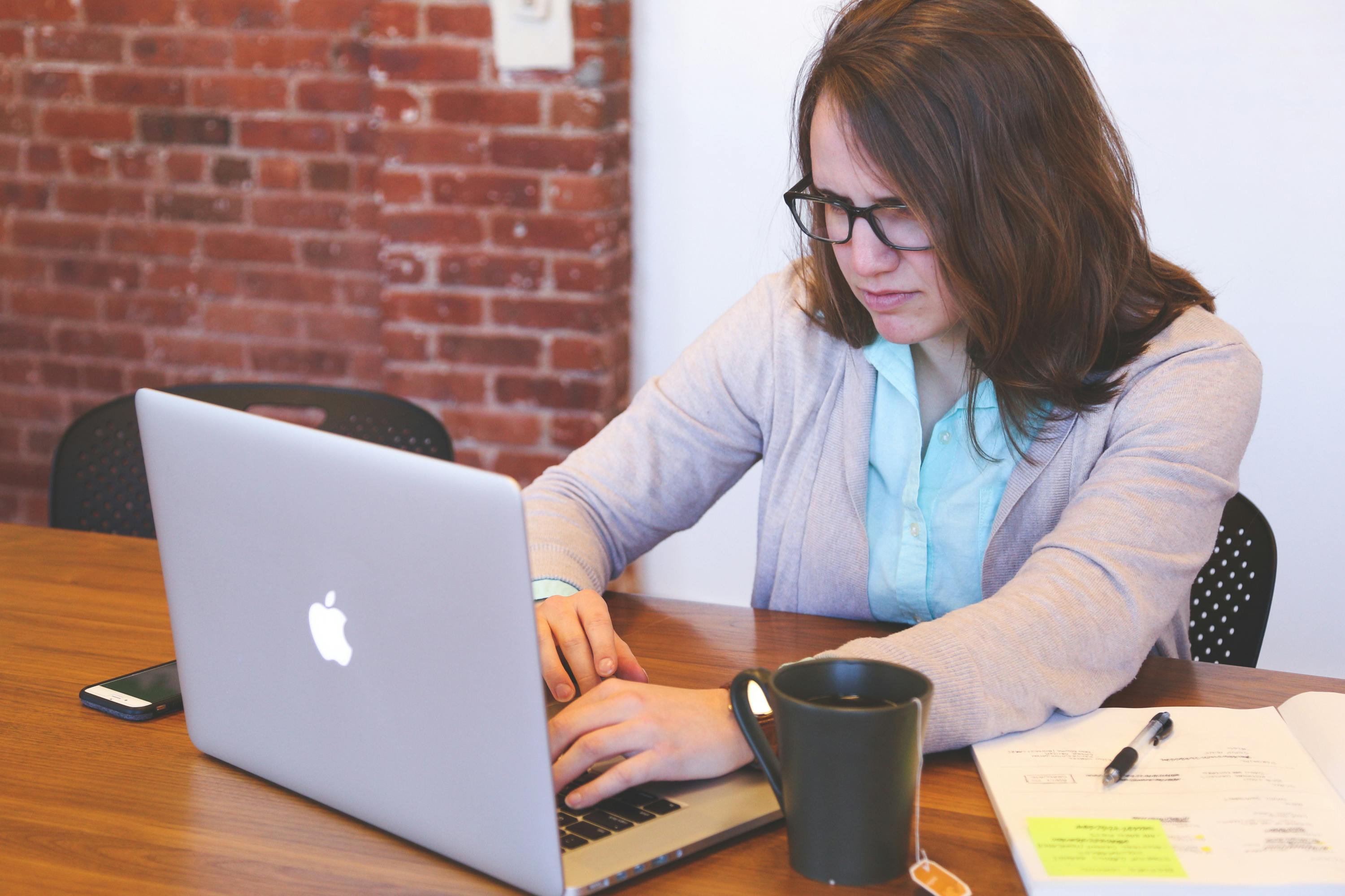 happy woman writing on a mac laptop at home