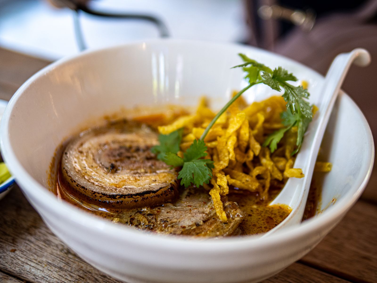 Close-up of khao soi, a Northern Thai curry noodle soup with crispy fried noodles and coriander