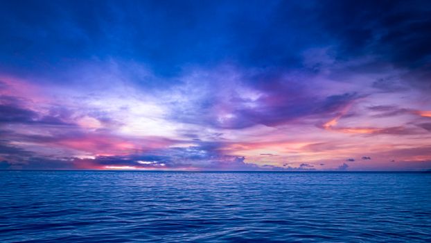 Stunning view of an ocean at sunset with vibrant purple and blue skies.