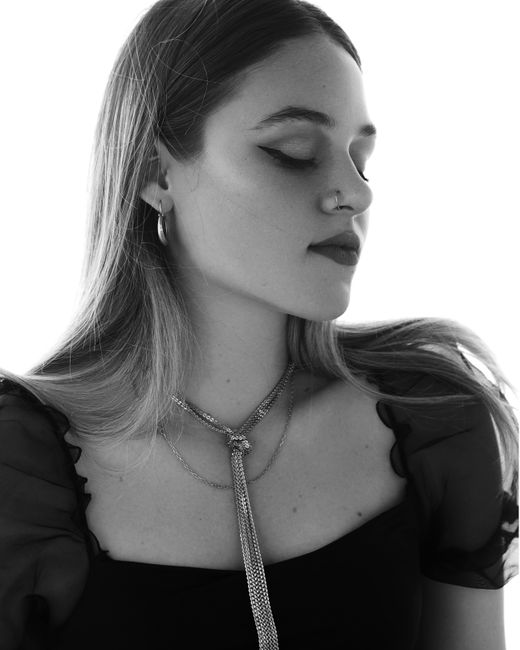 Black and white portrait of a woman wearing jewelry, closing her eyes gracefully.