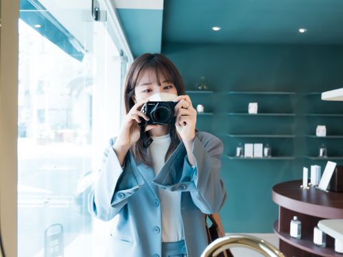 Free Asian woman in a blue blazer holding a camera indoors in Seoul, South Korea. Stock Photo