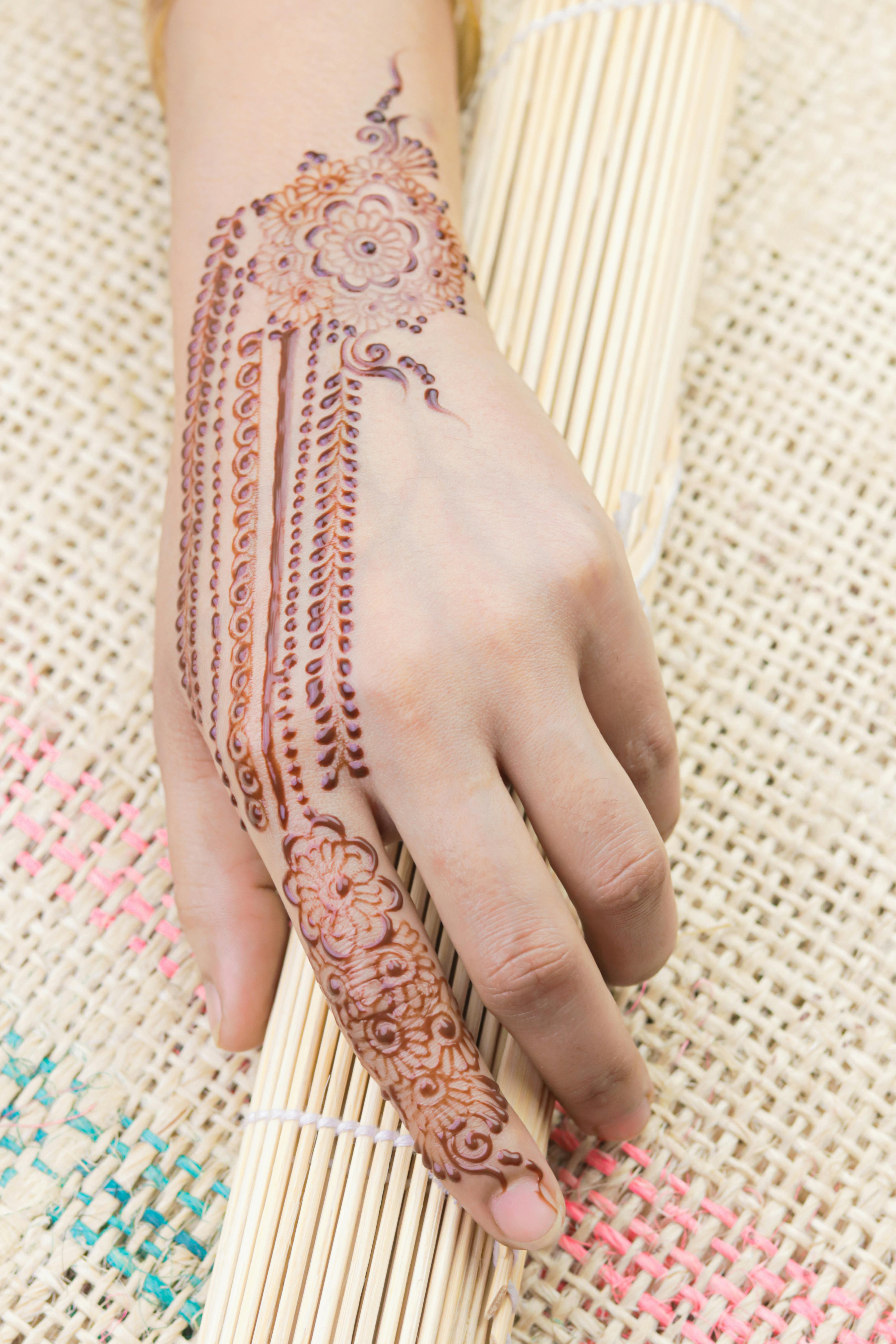 Henna tattoo on a hand and finger floral motif drawing henna being  applied to hand freshly applied still fresh Stock Photo  Adobe Stock