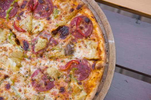 Close-up of savory pepperoni pizza with crispy crust on a rustic wooden table.